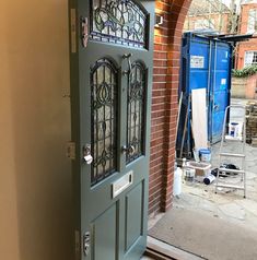 a blue door with stained glass on the side of a brick building in an alleyway