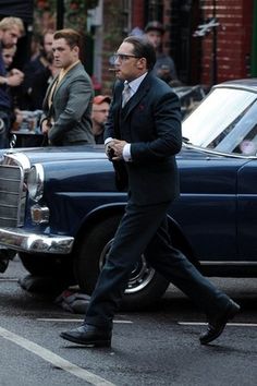 a man in a suit walking across the street