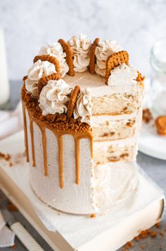 a cake with white frosting and caramel drizzled on top sitting on a table