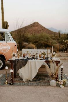 an orange van parked in front of a table with food on it and candles next to it