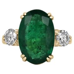 A classic emerald and diamond engagement, statement, or right-hand ring. Dexterously crafted in gleaming 14K gold this ring features a natural oval cut emerald that is set in a secure prong setting. This extraordinary emerald has a deep dark rare green color and glow. This emerald has very good eye clarity with natural Jardins that occur in all earth-mined emeralds. Brilliant round diamonds flank the emerald in a classic and desirable, three-stone setting. The ring is low profile and crafted in Right Hand Rings, Hand Ring, Yellow Gold Setting, Stone Setting, Three Stone Rings, Deep Green, Cool Eyes, Three Stone, Stone Settings