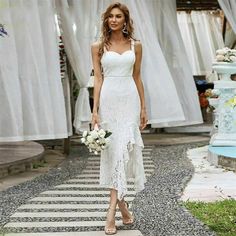 a woman in a white dress is walking down the street with flowers on her hand