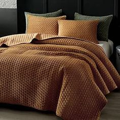 a bed covered in a brown bedspread and pillows