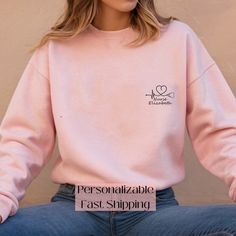 a woman sitting on the ground wearing a pink sweatshirt