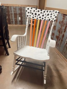 a white rocking chair with multicolored wooden slats on it's back