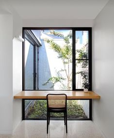 an empty room with a desk and chair in it, next to a large window