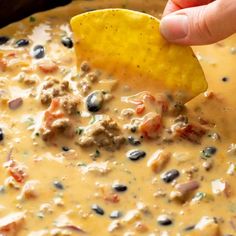 a hand dipping a tortilla chip into a bowl of quesadilla soup