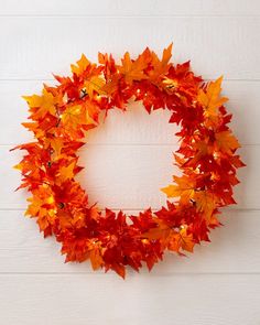 a wreath made out of autumn leaves on a white wall