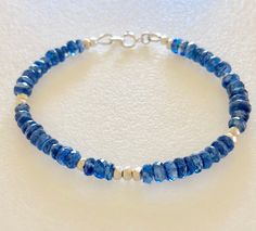 Gorgeous royal blue kyanite beaded gemstone bracelet accented with Karen Hill Tribe Fine Silver! Natural royal blue kyanite gemstones are faceted 5mm rondelles with lovely translucency. Thai fine silver faceted cubes are all handmade by the Karen Hill Tribe of northern Thailand. This amazing silver is .997 to .999 with a lustrous finish. Bracelet is made to order in your size. Closes with .925 Sterling silver spring ring clasp and matching findings. Handmade Blue Apatite Bracelets, Adjustable Blue Apatite Bracelets, Blue Rondelle Beaded Bracelets, Blue Faceted Rondelle Bracelets, Blue Gemstone Beads Rondelle Beaded Bracelets, Blue Rondelle Gemstone Beaded Bracelets, Blue Rondelle Bracelets With Natural Stones, Fun Halloween Earrings, Kyanite Bracelet