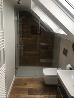 a bathroom with a toilet, sink and glass shower stall in it's corner