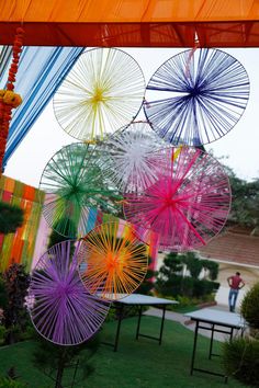 colorful umbrellas are hanging from the ceiling in an outdoor setting with tables and chairs