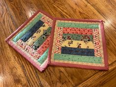 two quilted placemats sitting on top of a wooden floor next to each other