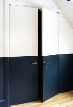 an empty room with two blue and white doors on the wall next to a wooden floor