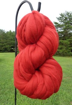 two skeins of red yarn sitting on top of a black pole in the grass