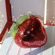 a shiny red apple sitting on top of a white table