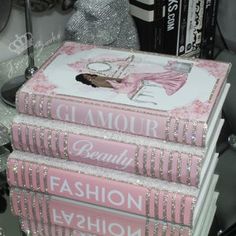 a stack of pink books sitting on top of a glass table next to a bottle