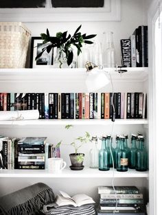 a book shelf filled with lots of books and vases on top of it's shelves