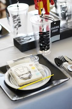 the table is set with black and white plates, silverware, and plastic utensils