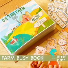 a child's hand holding up a small book with farm animals on it