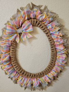 a wreath made out of burlocks and lace with a bow on it hanging on the wall