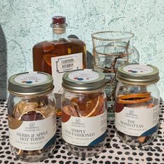 four jars filled with different types of food on a table next to a glass cup