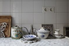 the kitchen counter is covered with dishes and utensils, including teapots