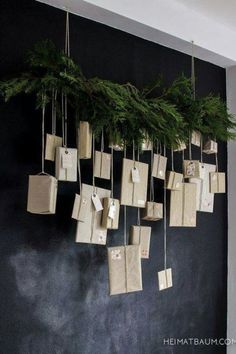 a bunch of bags hanging on a wall with christmas tree branches in the middle and tags attached to them