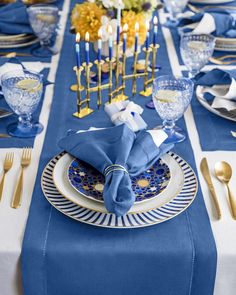 a table set with blue and gold place settings