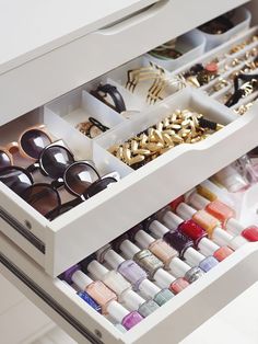 an open drawer with many pairs of sunglasses and nail polishes in it on the bottom shelf