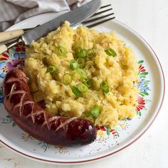 a hot dog and mashed potatoes are on a plate with a fork next to it