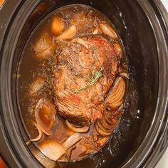 a slow cooker filled with meat and onions