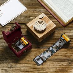 an old fashioned camera sitting on top of a wooden table next to a roll of film