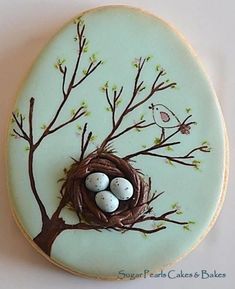 a cookie decorated like a bird's nest with three eggs in the tree branches