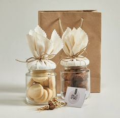 two jars filled with different types of food next to a brown paper bag and tag