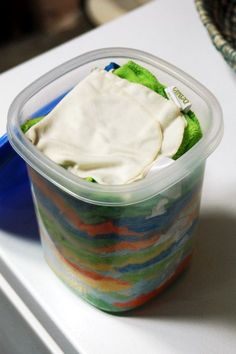 a plastic container filled with food sitting on top of a white counter next to a blue bowl