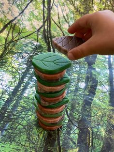 a stack of green and red cookies sitting on top of a tree stump in the woods