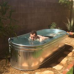 a man swimming in a large metal tub