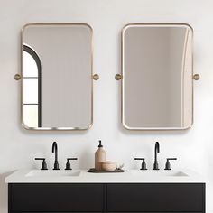 two mirrors on the wall above sinks in a white bathroom with black and gold fixtures