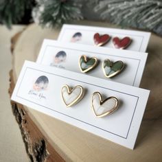 three heart shaped pins sitting on top of a piece of paper next to a christmas tree