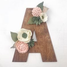 a wooden letter decorated with flowers and leaves