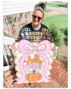 a woman holding up a sign that says hello pumpkin with a big bow on it