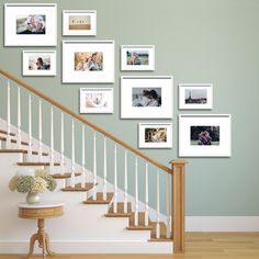 a staircase with pictures on the wall and a table in front of it, along with a vase filled with flowers