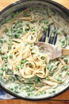 a pan filled with pasta and peas on top of a wooden table