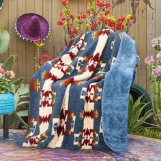 a blue blanket sitting on top of a table covered in flowers and plants next to a wooden fence