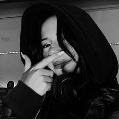 black and white photograph of a woman wearing a hoodie holding her finger up to her mouth