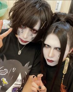 two people with makeup on their faces posing for the camera