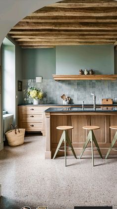 a kitchen with two stools in front of an island