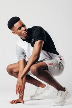 a man kneeling down in front of a white background with his foot on the ground