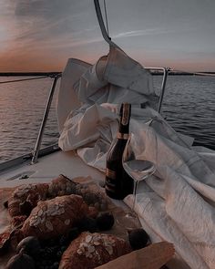 bread and wine are sitting on the deck of a sailboat at sunset or dawn