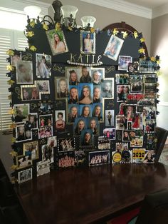 a wooden table topped with pictures and frames covered in photos next to a wall hanging on the wall